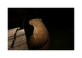 A carved wooden beaver bow and arrow track target figurine illuminated by a warm spotlight against a dark outdoor background, positioned next to a weathered wooden plank.